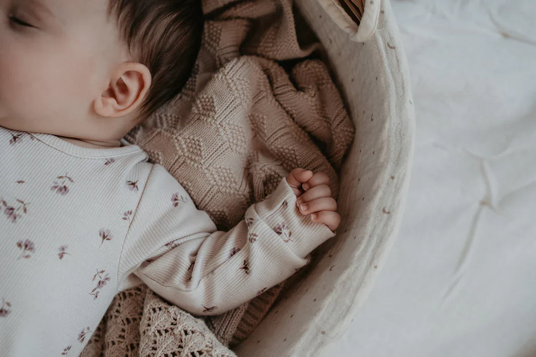 Nyfødt baby sover trygt på blødt tæppe under lur eller nattesøvn