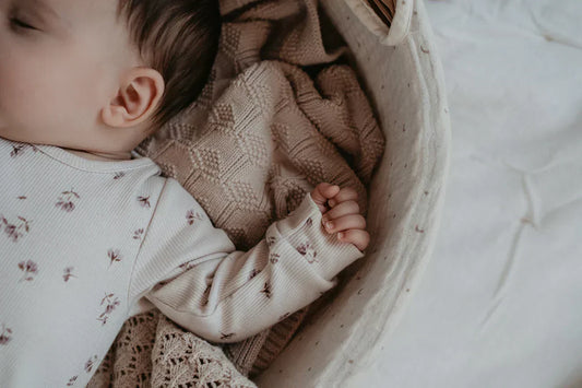 Nyfødt baby sover trygt på blødt tæppe under lur eller nattesøvn
