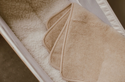 Merinould rullemadras til baby i naturlig beige farve, der skaber en blød, temperaturregulerende og komfortabel soveplads i tremmeseng eller barnevogn.