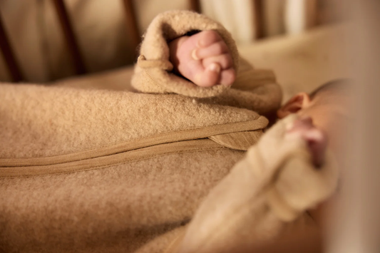 Nærbillede af babysoveposens lynlås og ærme i filtet merinould
