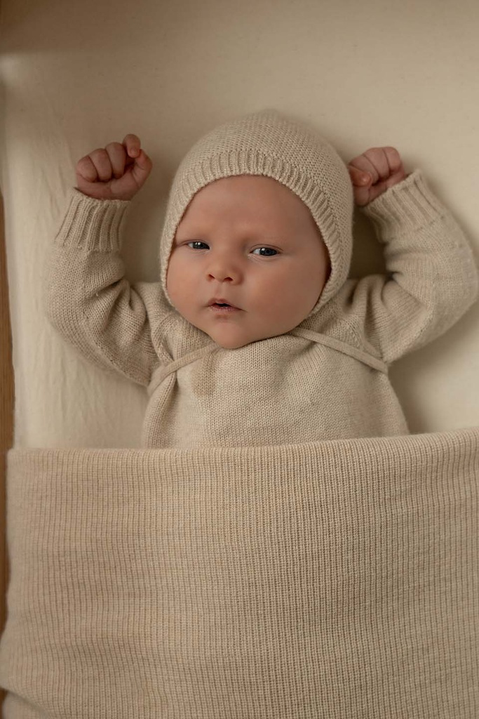 Nyfødt baby med merinould baby kyse fra Hvid i Cream ligger i sengen