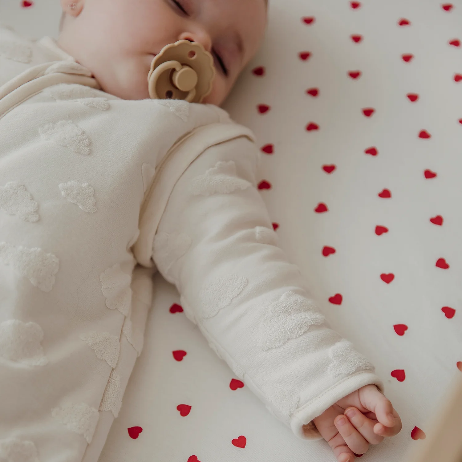 Baby sover på jersey lagner med hjertemønster