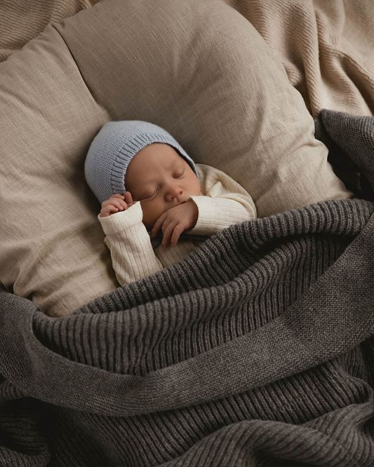 Sovende nyfødt baby med uld baby kyse fra Hvid i Sky under strikket tæppe