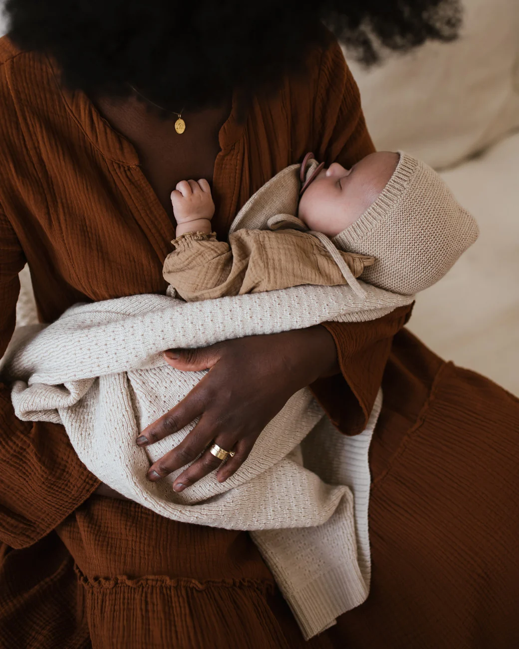 Sovende baby med strikket babyhjelm i merinould fra Hvid i armene