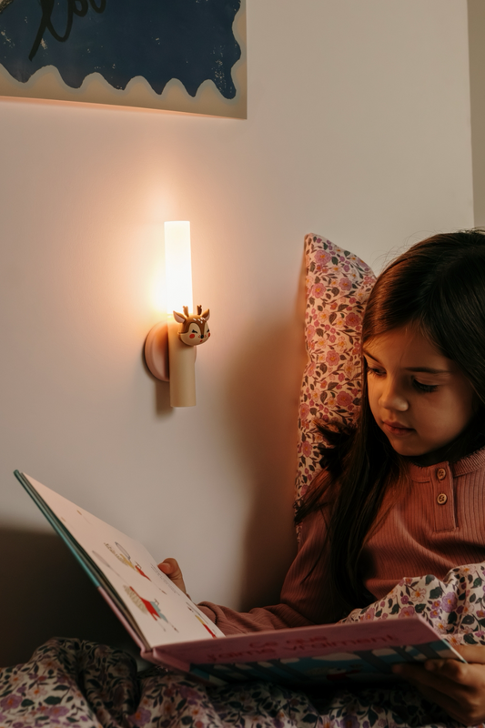 Barn læser godnathistorie med The Zoo Family lampe Hjort på væggen ved sengen – blødt lys skaber hyggelige og trygge læsestunder.