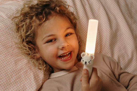 The Zoo Family lampe Koala som natlampe til børn – barn holder den genopladelige børnelampe i sengen ved sengetid for ekstra tryghed i mørket.