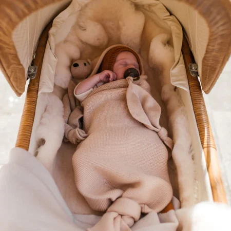 Baby ligger trygt i strikket merinould cocoon i farven oat fra Hvid – perfekt til korte lure og hygge.
