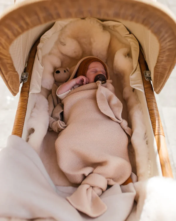 Baby ligger trygt i strikket merinould cocoon i farven oat fra Hvid – perfekt til korte lure og hygge.