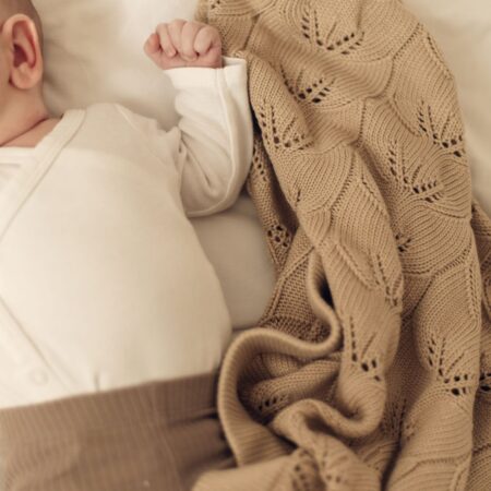 Baby sover trygt under cappuccinofarvet babytæppe i bambus fra ColorStories