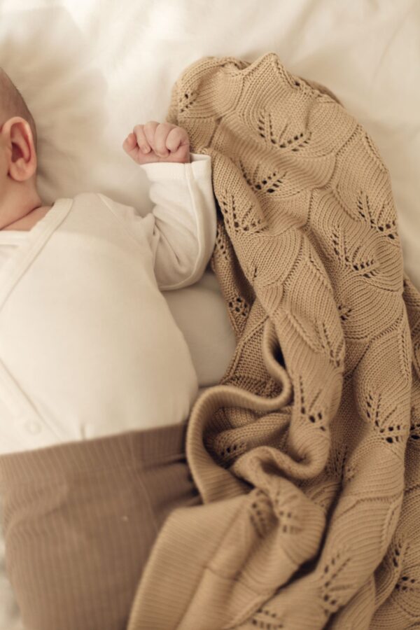 Baby sover trygt under cappuccinofarvet babytæppe i bambus fra ColorStories
