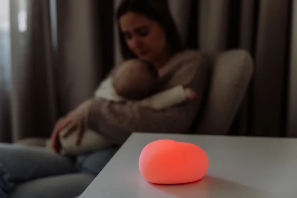 Ammelampe med blødt lys ved natamning – mor sidder med baby i sengen | MrsMama