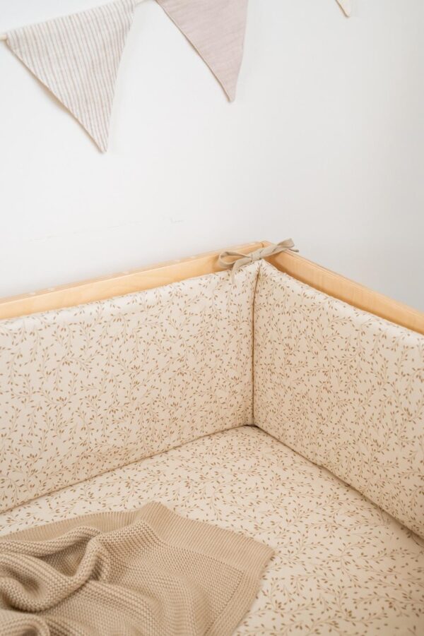Sengerand til baby i beige bomuld med fint bladmotiv – blød og sikker beskyttelse til tremmeseng 120x60 cm.