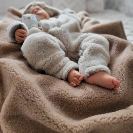 Baby ligger trygt og sover på blødt baby uldtæppe i lammeuld – naturligt og åndbart tæppe til baby