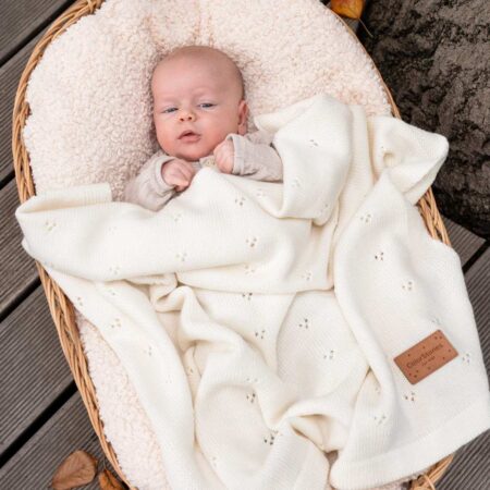 Baby ligger trygt under et blødt merino babytæppe i cremefarvet uld – naturligt og åndbart tæppe til baby