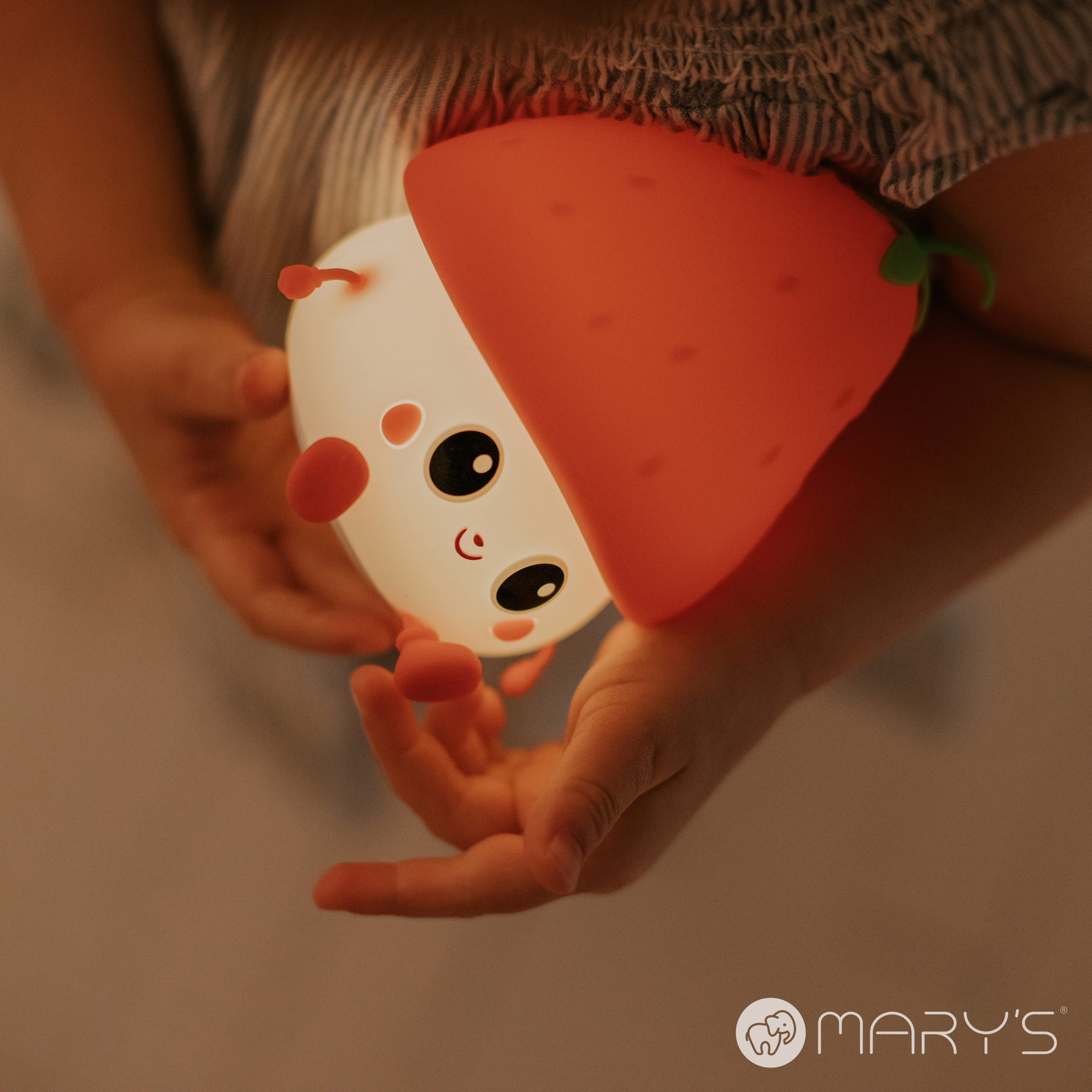 Natlys til børn formet som et sødt jordbær fra Mary’s, holdt af barn – blødt og varmt LED natlys til tryg puttetid.