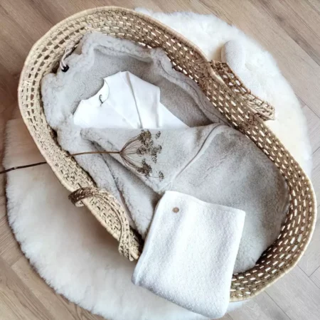 Uld kørepose til autostol i beige uld som lifestyle-opstilling i Moseskurv