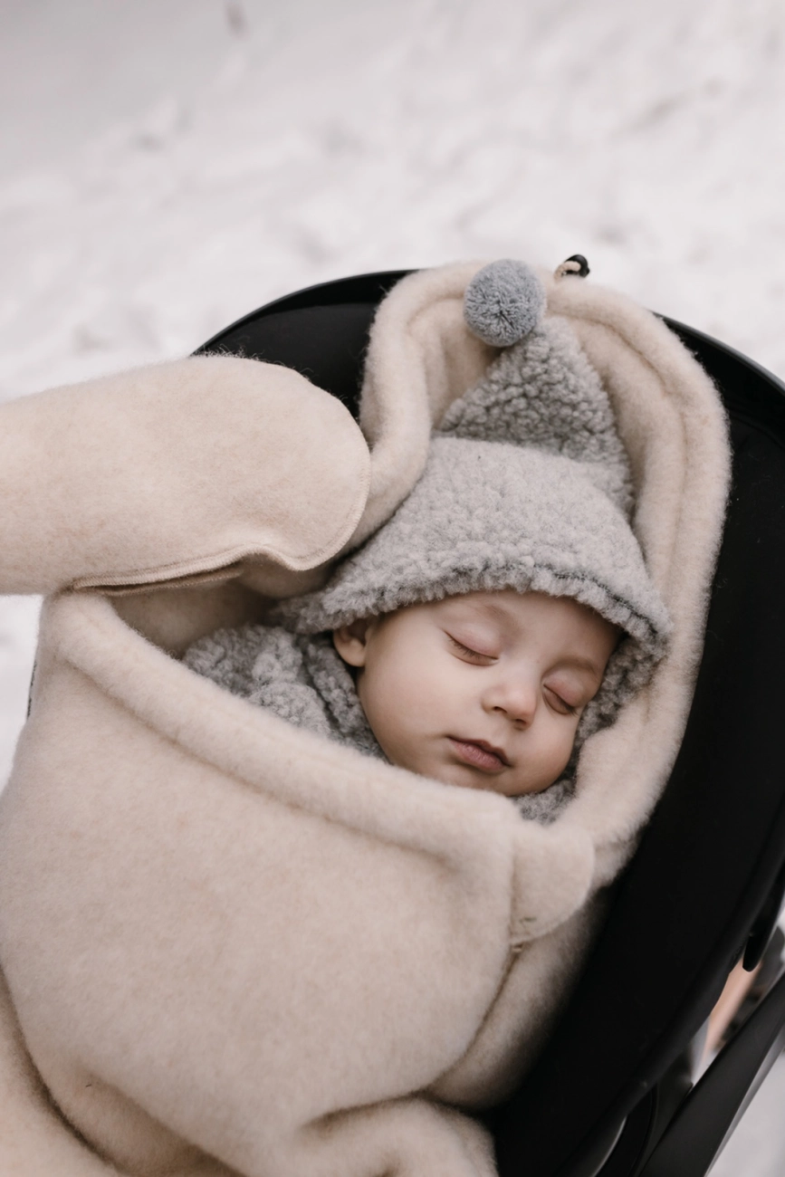 Baby sover trygt i en kørepose i 100 % naturlig uld til baby – blød, åndbar og perfekt til vinterens kolde dage.