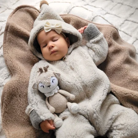 Baby sover trygt i ulddragt Nevada i beige – 100 % ren uld heldragt med hætte og ombuk ved hænder og fødder. Perfekt til vinter og kolde dage.