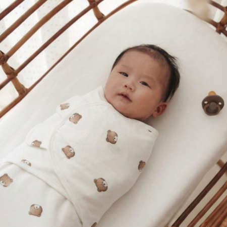 Baby svøbt i blødt babysvøb med bjørnemotiv, som giver tryghed og bedre søvn