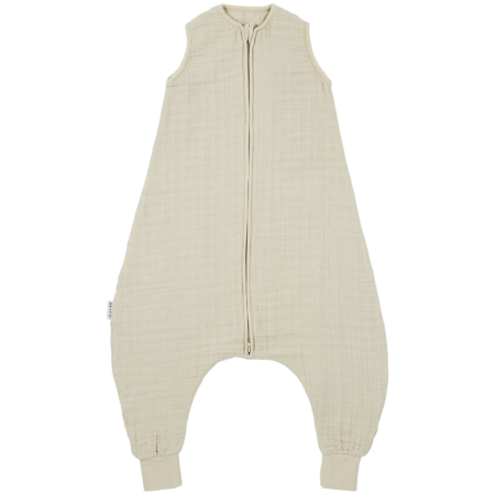 Sovepose med ben i musselin i sand set forfra